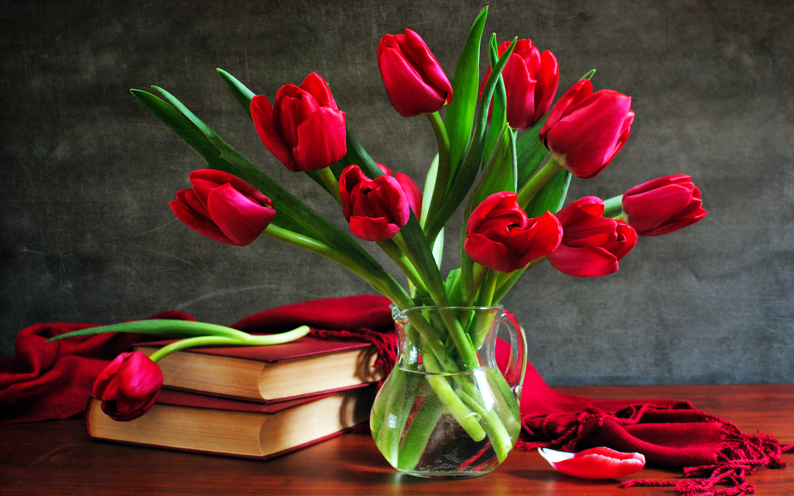 Red tulip, pitcher, scarf, and book on a desktop. Classic still life photography.