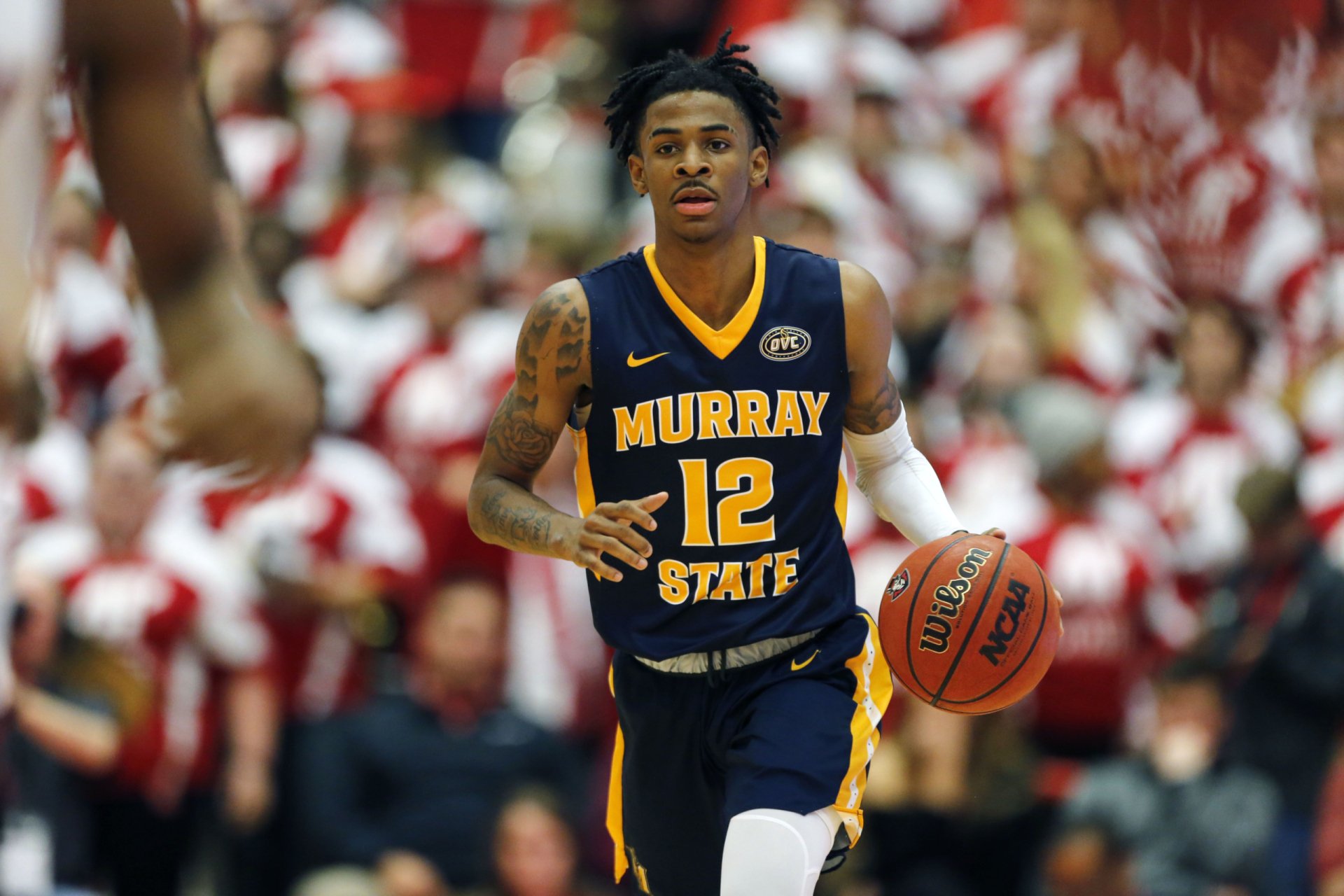 2K Quad HD PC desktop wallpaper: college basketball player in Murray State navy‑gold No.12 jersey dribbling downcourt with a cheering crowd filling the arena.