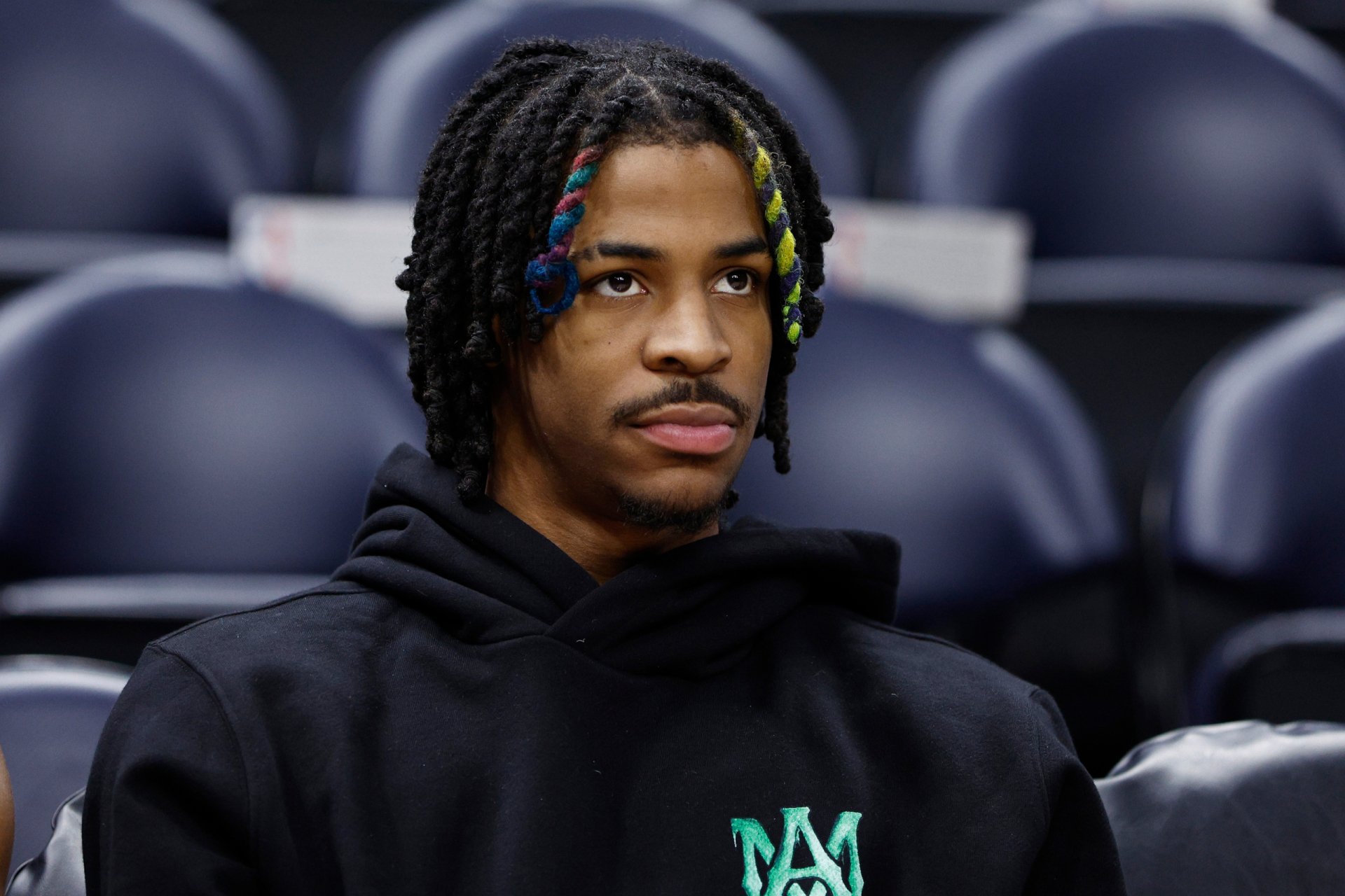 HD desktop wallpaper featuring basketball player Ja Morant in a black hoodie, captured in a candid moment during a sports event.