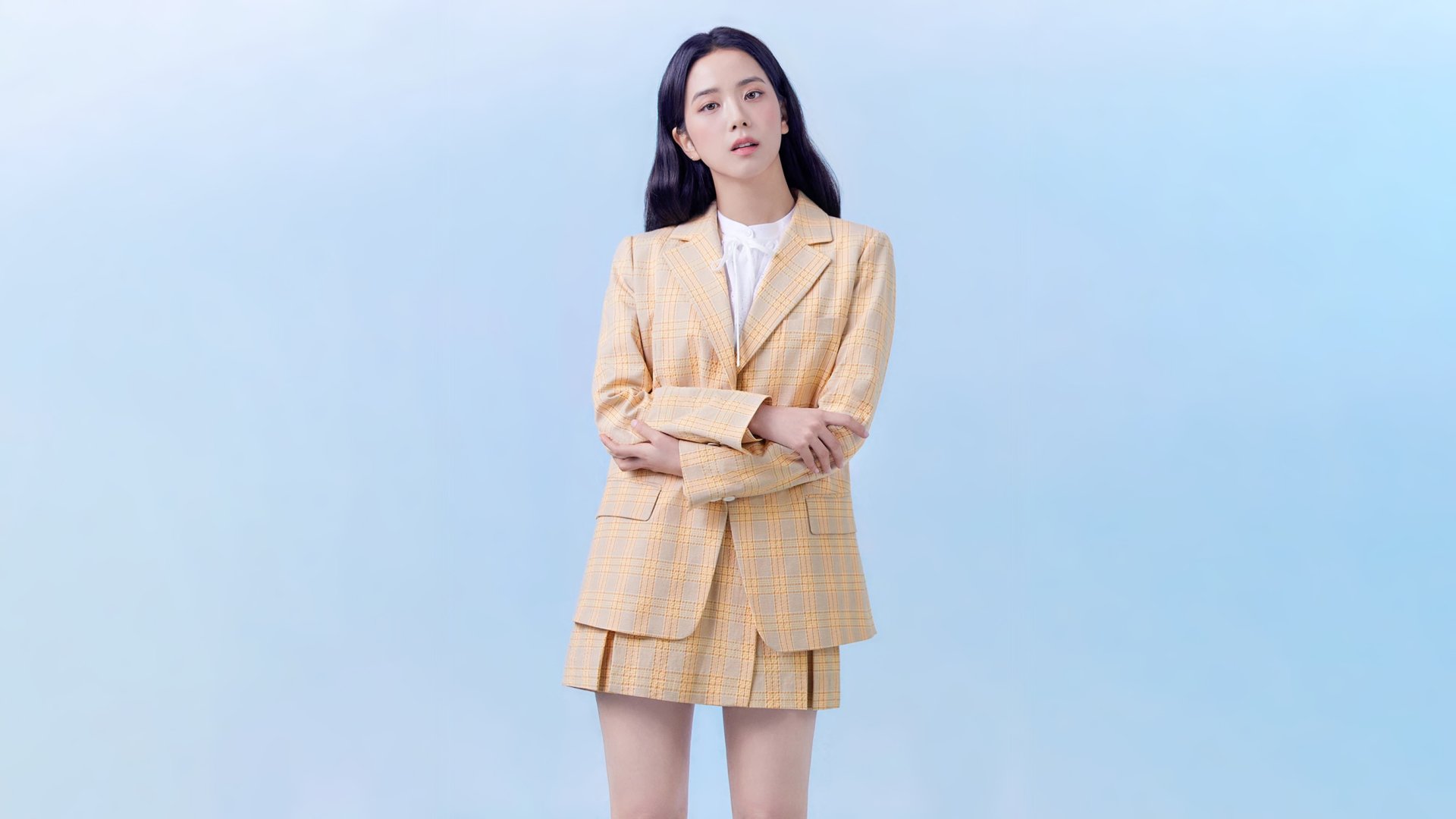 HD desktop wallpaper featuring Jisoo of BlackPink dressed in a beige plaid suit against a light blue background, highlighting her as a prominent music artist.
