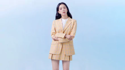 HD desktop wallpaper featuring Jisoo of BlackPink dressed in a beige plaid suit against a light blue background, highlighting her as a prominent music artist.