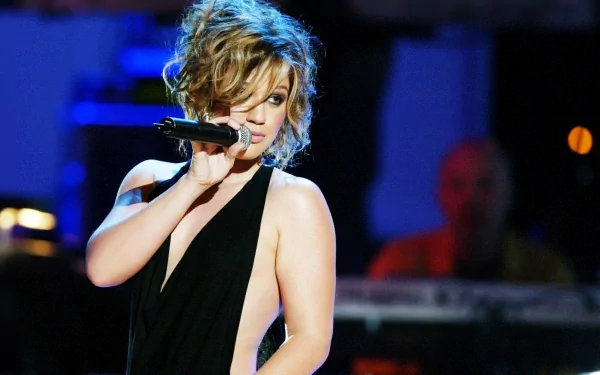 HD PC desktop wallpaper featuring Kelly Clarkson passionately singing on stage, showcasing her music performance with vibrant lighting and dynamic energy.