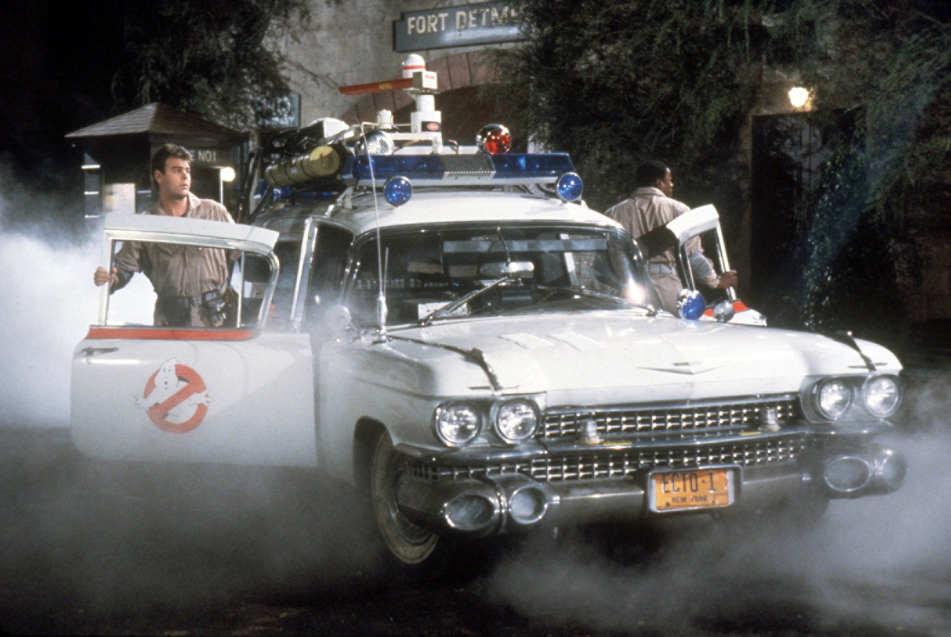 HD PC desktop wallpaper featuring the Ghostbusters movie scene with the iconic Ecto-1 car surrounded by mist and characters preparing for action.