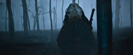 Prey (2022) movie 2K Quad HD PC wallpaper: masked Predator silhouette with circular armor and blade in a foggy forest, bathed in blue-green cinematic light.