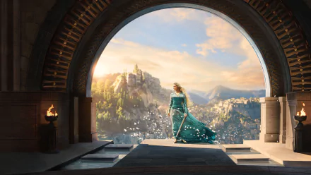 Cannot identify the person. Alt: HD desktop wallpaper of a robed woman from The Lord of the Rings: The Rings of Power, standing on an arched balcony overlooking a sunlit city.