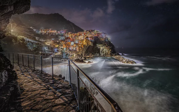Night view of Manarola's colorful cliffside buildings overlooking the ocean, captured in a high-definition man-made scene for a PC desktop wallpaper and background.