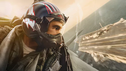HD PC desktop wallpaper featuring a close-up of a pilot wearing a helmet from the movie Top Gun: Maverick, set against the backdrop of an aircraft carrier and sky.
