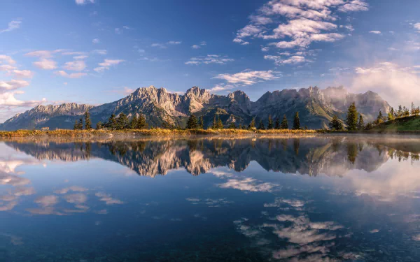 4K Ultra HD desktop wallpaper of Austria’s nature featuring a serene mountain range reflected perfectly in a calm lake under a partly cloudy sky.