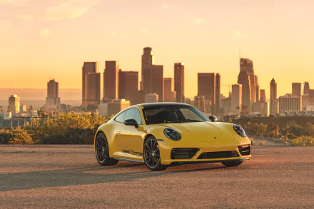 Yellow Porsche 911 Carrera T parked with a city skyline at sunset, captured in stunning 4K Ultra HD for a PC desktop wallpaper backdrop.