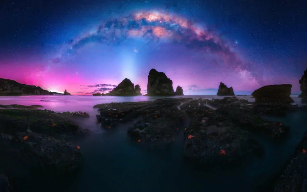 A stunning 4K Ultra HD night landscape of rocky shoreline beneath the vibrant Milky Way stretching across the sky in nature’s serene beauty.