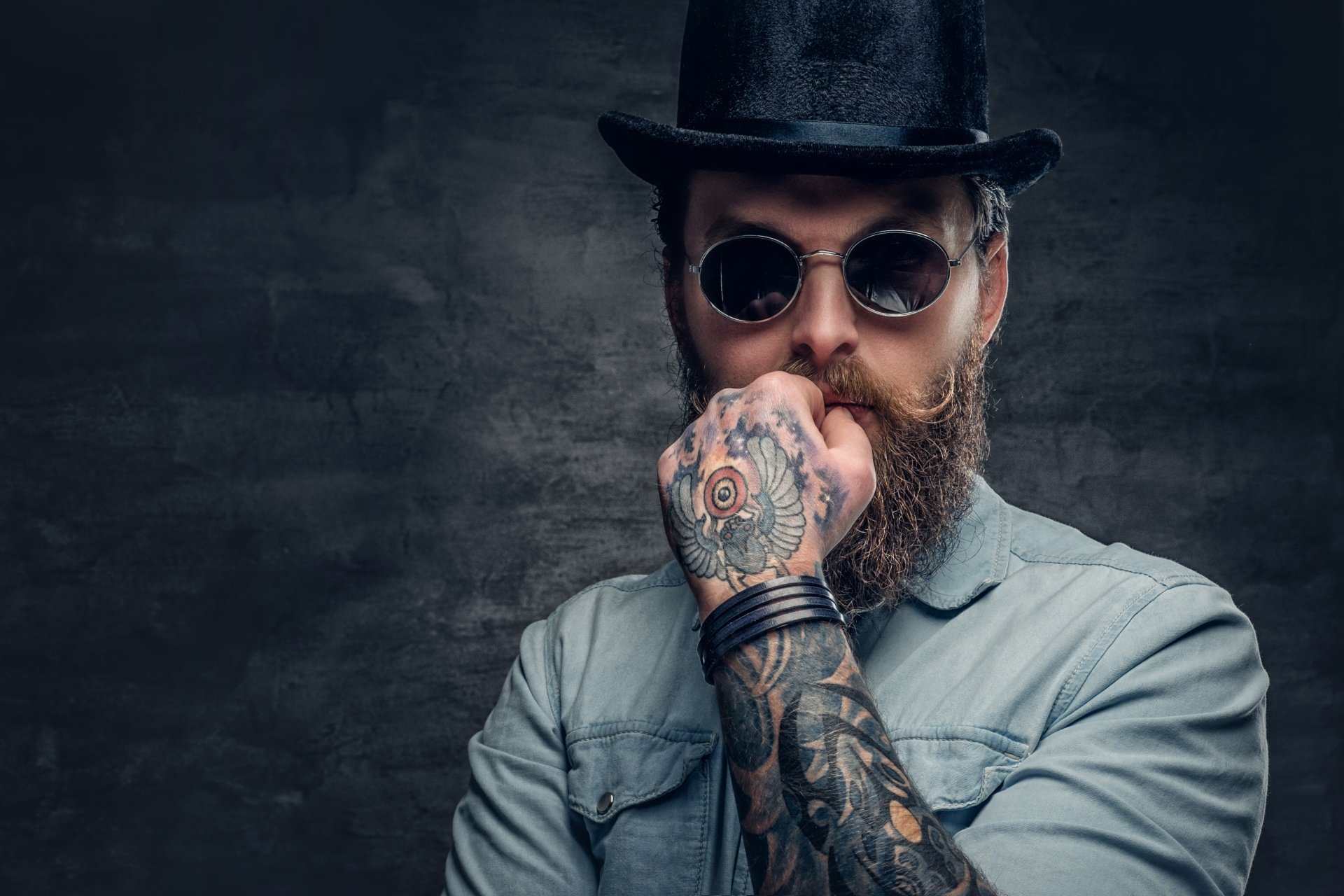 A confident tattooed man posing as a model in a high-definition desktop wallpaper and background.