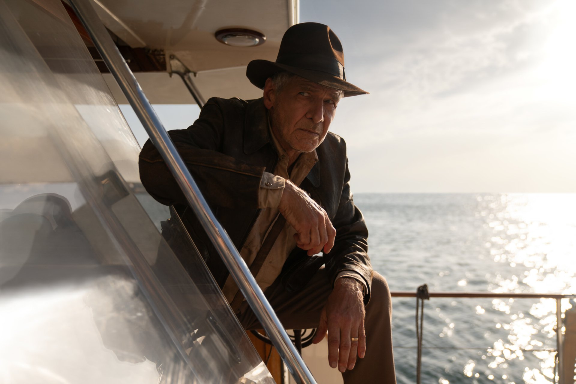 HD desktop wallpaper featuring Harrison Ford as Indiana Jones from the movie Indiana Jones and the Dial of Destiny, set against a serene ocean backdrop.