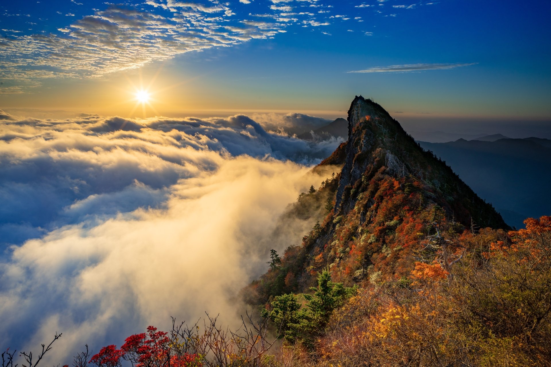 4K Ultra HD desktop wallpaper of a mountain peak rising above a sea of clouds under a vibrant horizon at sunrise, showcasing stunning natural landscape beauty.
