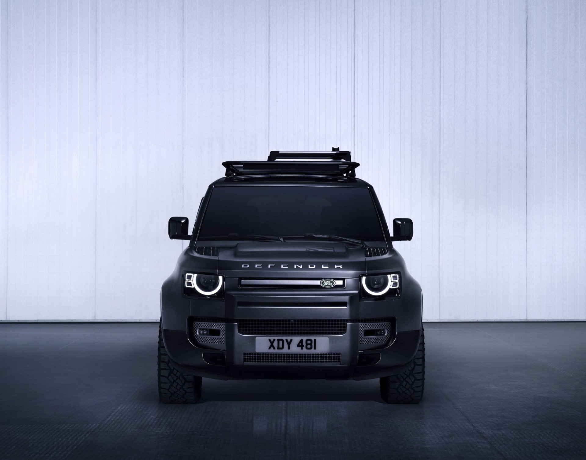 Front view of a black Land Rover Defender parked indoors, captured in sharp detail for a 4K Ultra HD PC desktop wallpaper and background.