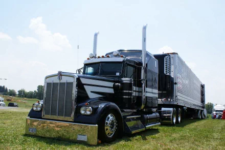 4K Ultra HD desktop wallpaper featuring a sleek black Kenworth truck parked on grass under a clear sky.