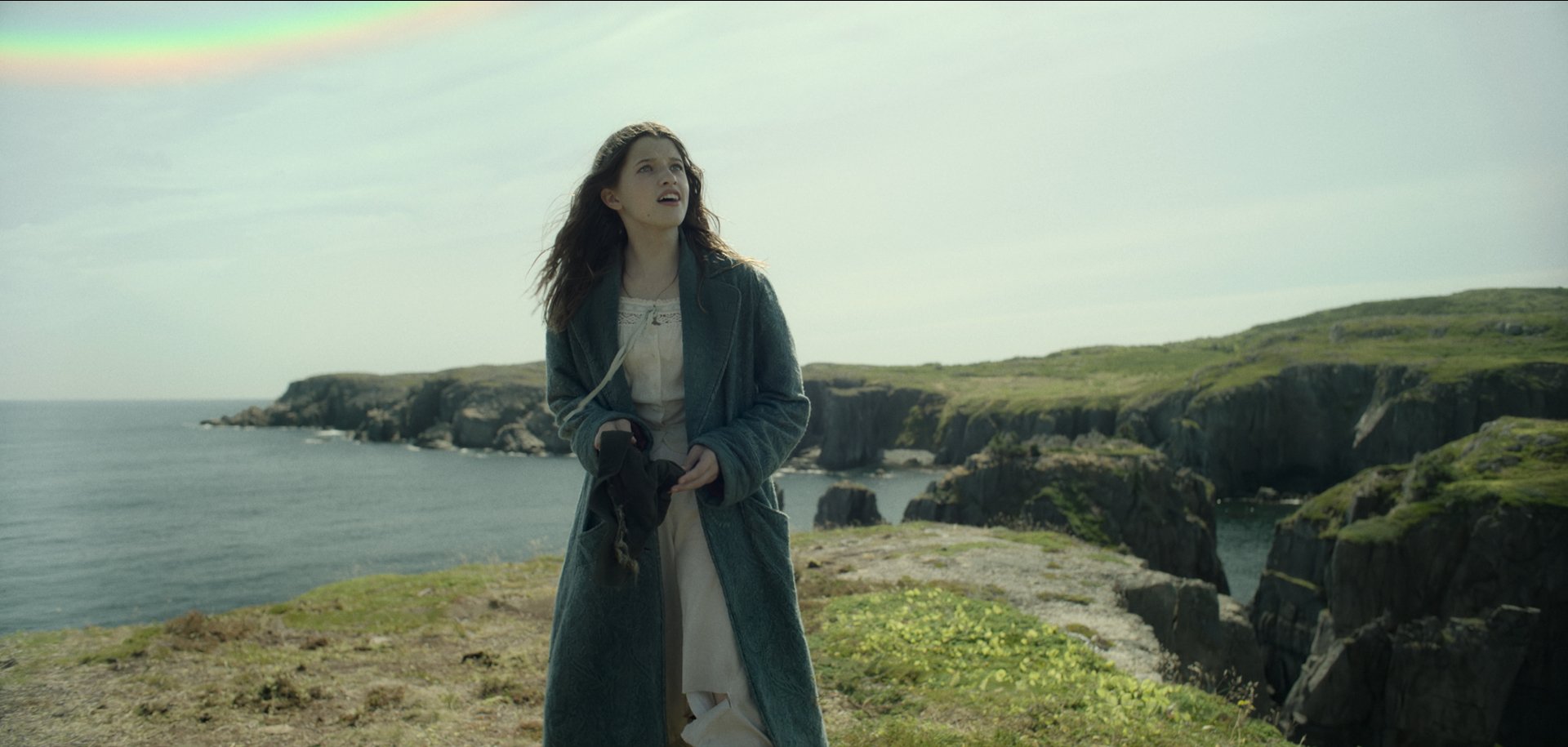 HD wallpaper featuring a Wendy-inspired character from Peter Pan, standing on a grassy cliff with the ocean in the background, reflecting the sense of adventure from the classic tale.