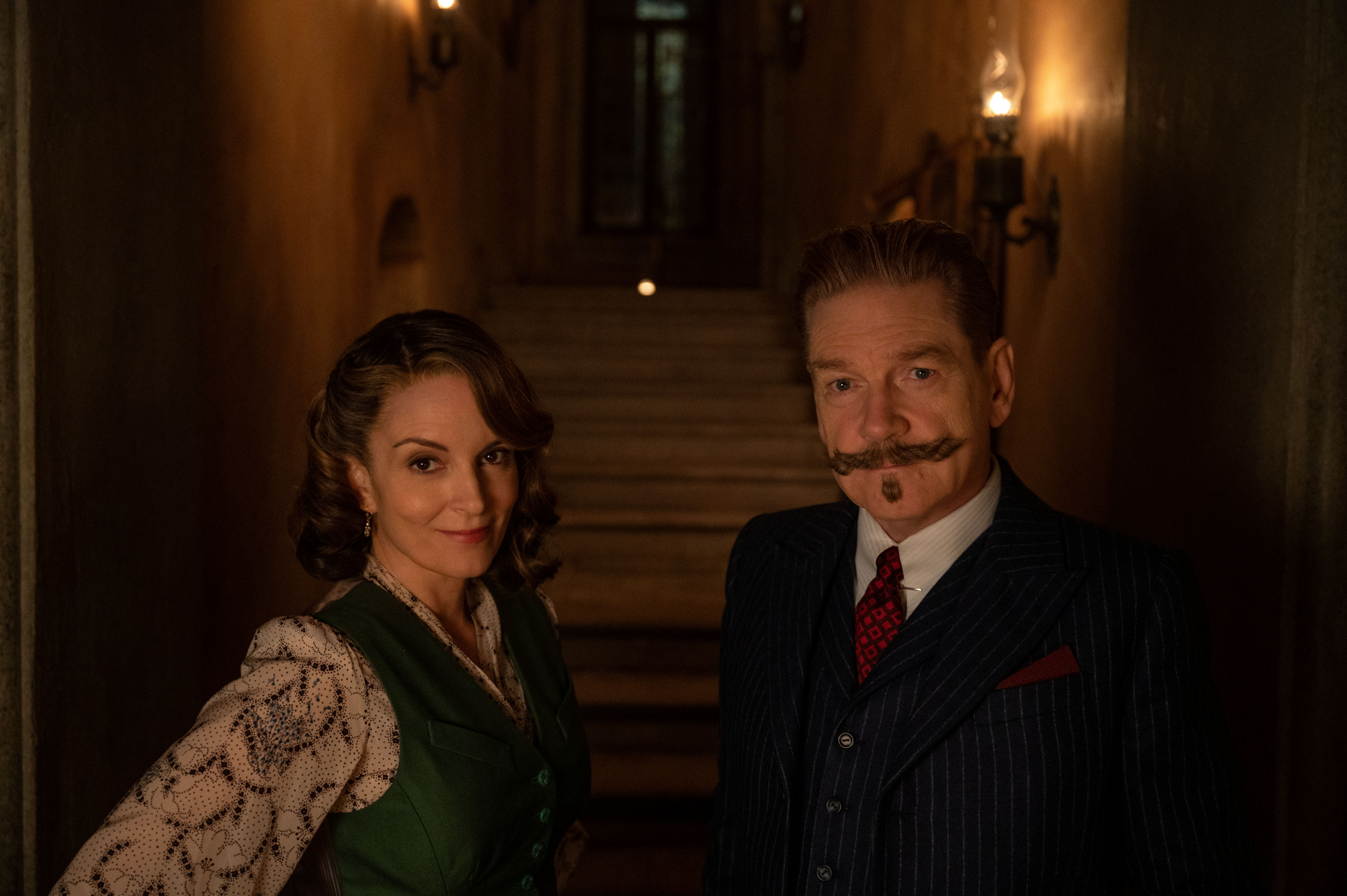 HD desktop wallpaper featuring two actors in 1930s attire standing in a moody, dimly lit hallway, promoting the film A Haunting in Venice.