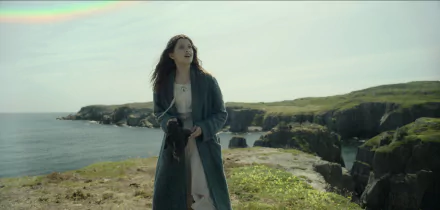 HD wallpaper featuring a Wendy-inspired character from Peter Pan, standing on a grassy cliff with the ocean in the background, reflecting the sense of adventure from the classic tale.