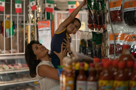 HD wallpaper of a heartwarming moment with a smiling woman lifting a young boy in a grocery store aisle, with shelves full of spicy Flamin' Hot snacks in the background.