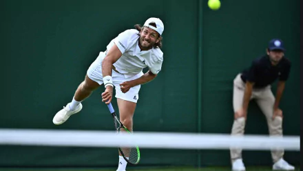 Lucas Pouille serving during Wimbledon 2023, showcasing his skill in tennis. A dynamic sports moment captured as he prepares to hit the ball.