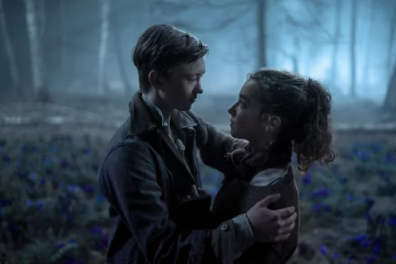 A romantic scene from the movie White Bird, featuring two young characters embracing amidst a misty forest backdrop filled with blue flowers, creating an emotional atmosphere.