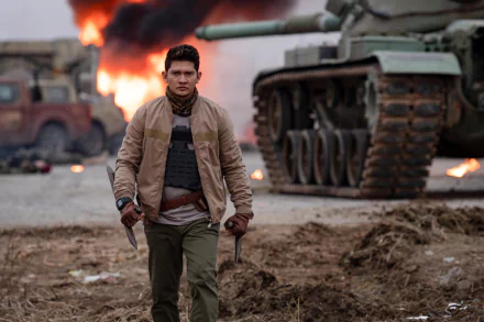 Iko Uwais strides confidently through a war-torn scene in Expend4bles, with flames and military vehicles in the background. This HD image serves as a striking desktop wallpaper.