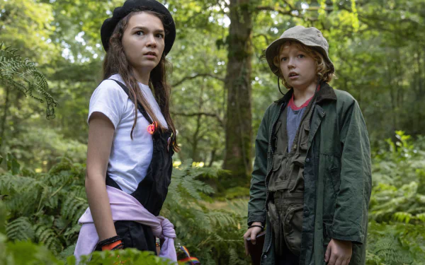 Two children looking alert in a forest setting, potentially a scene from the Cocaine Bear movie, available as a high-definition desktop wallpaper and background.