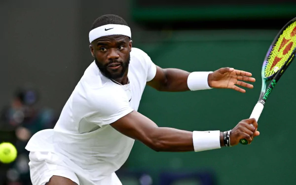 HD desktop wallpaper of Frances Tiafoe in action at Wimbledon 2023, focused and ready to hit a tennis ball.