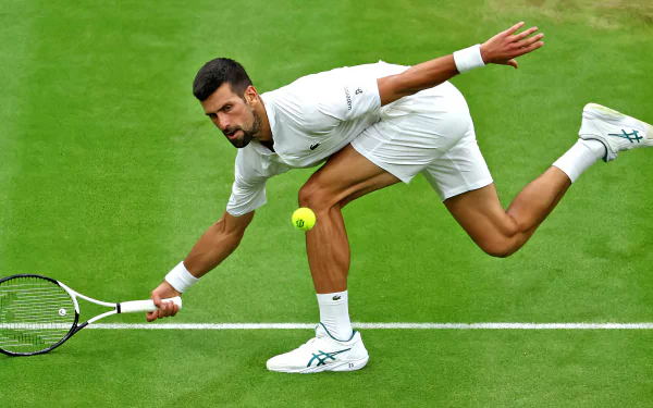 Novak Djokovic in action at Wimbledon 2023, showcasing his agility and skill on the grass court during a tense moment in a tennis match. Sports wallpaper capturing the intensity of the game.