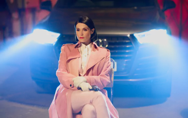 Woman in pink trench coat sitting in front of a car with headlights on, mysterious night scene for desktop wallpaper tagged with culprits.