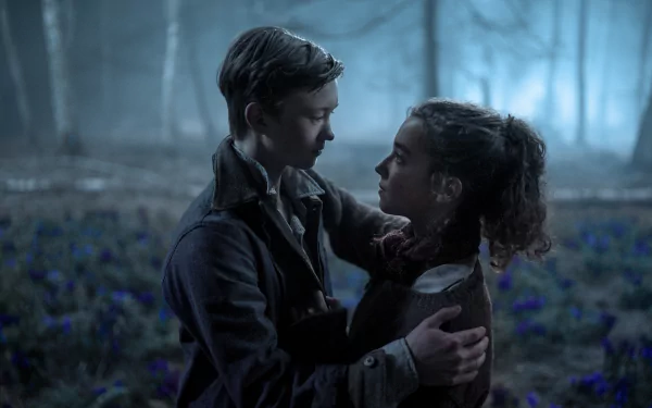 A romantic scene from the movie White Bird, featuring two young characters embracing amidst a misty forest backdrop filled with blue flowers, creating an emotional atmosphere.