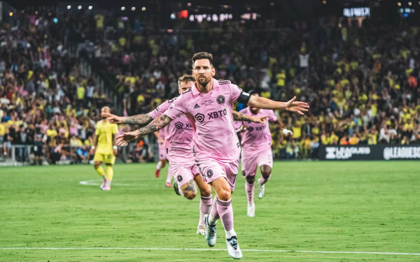 HD wallpaper featuring an Inter Miami CF player in pink kit celebrating on the pitch in front of exuberant fans, invoking the dynamic spirit of soccer.
