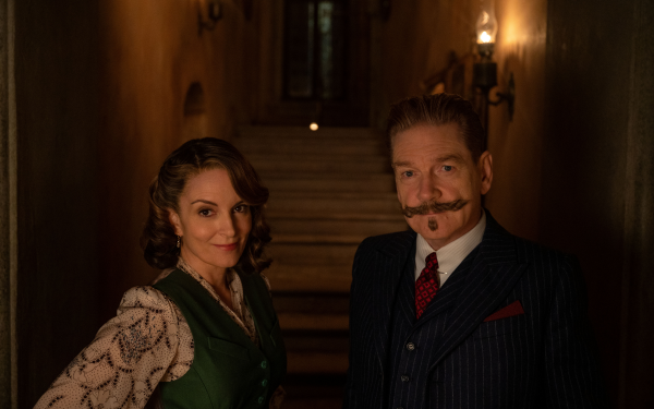 HD desktop wallpaper featuring two actors in 1930s attire standing in a moody, dimly lit hallway, promoting the film A Haunting in Venice.