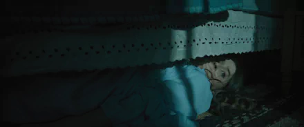 Eerie HD wallpaper featuring a person lying under the bed with a fearful expression, tagged with No One Will Save You, suitable as a suspenseful desktop background.