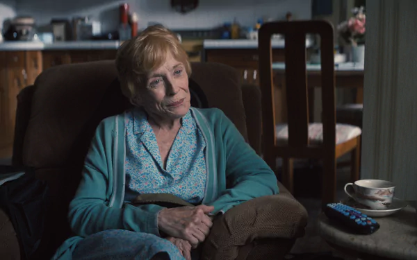 HD desktop wallpaper featuring an elderly woman, tagged as 'Quiz Lady,' sitting in a cozy home environment with a thoughtful expression, accompanied by a cup and saucer, suggesting a moment of contemplation or rest.