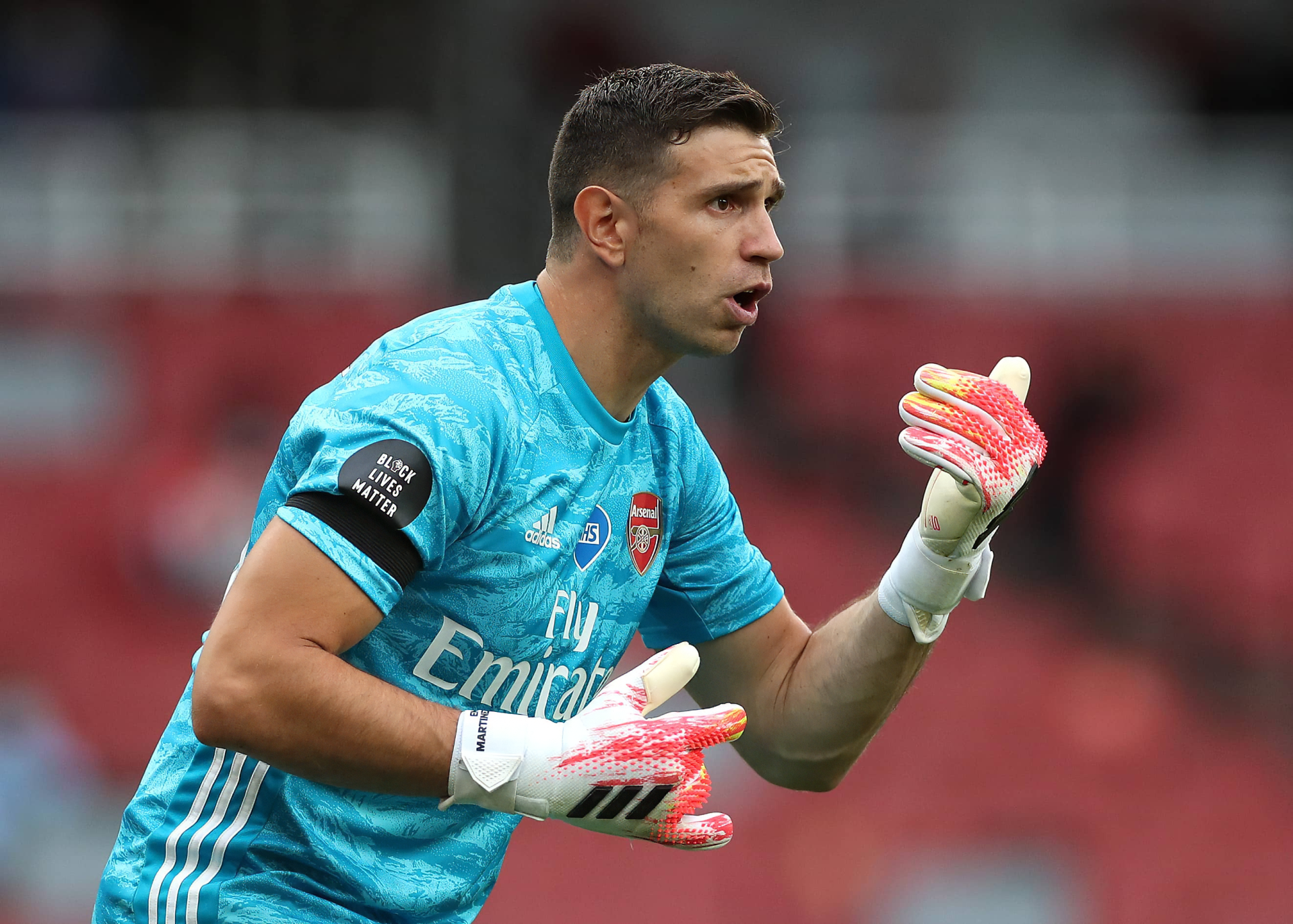 HD desktop wallpaper featuring a focused soccer goalkeeper in action, wearing a teal kit with an Emirates sponsor logo.