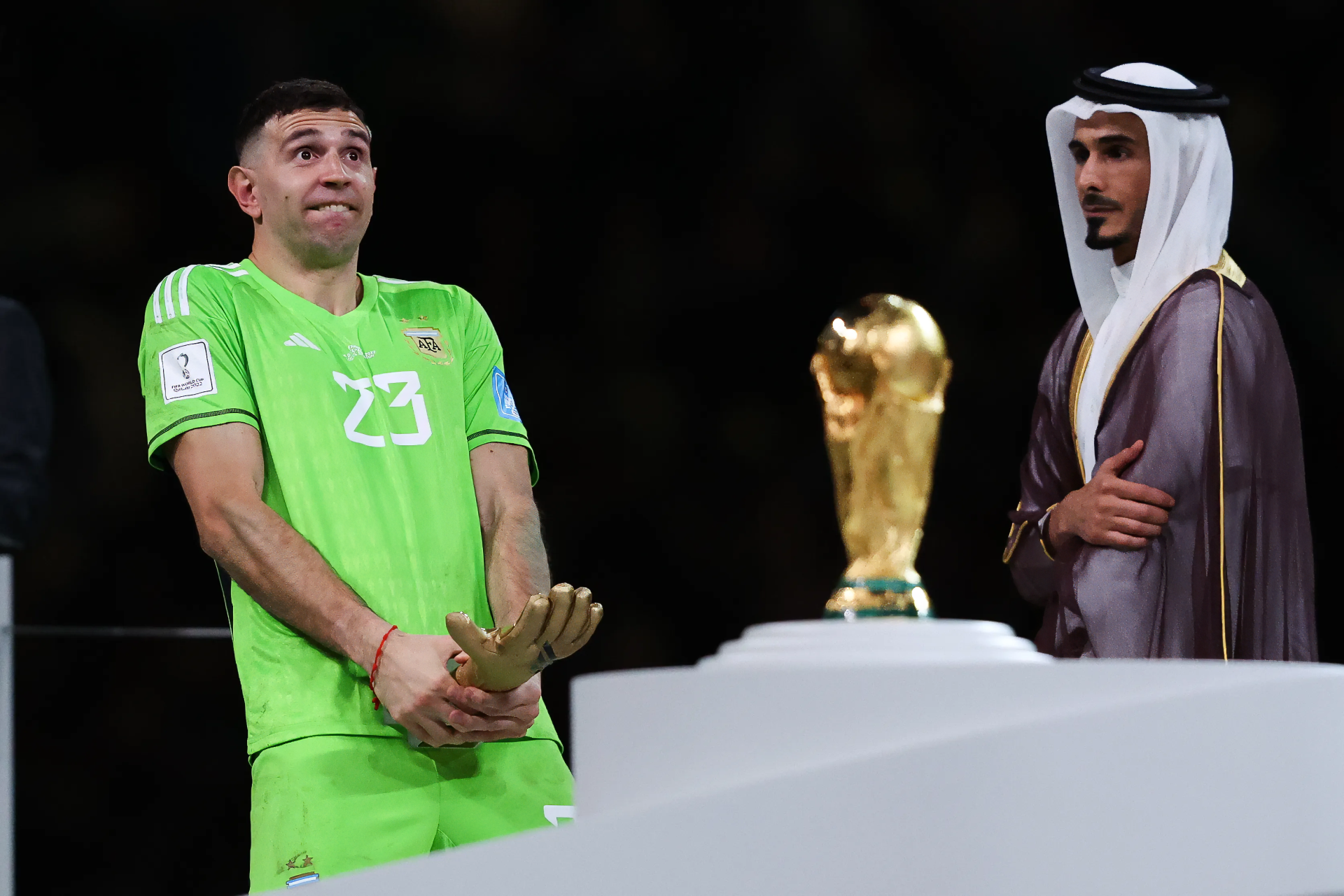 Soccer player Emiliano Martinez stands beside the World Cup trophy, captured as a high-definition desktop wallpaper.