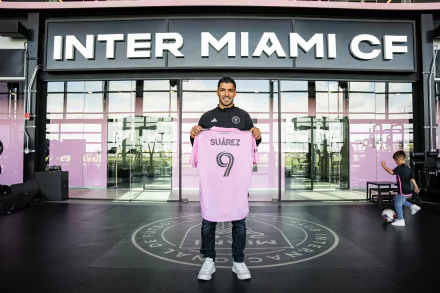 Luis Suárez poses proudly with his Inter Miami CF jersey as the team logo and modern facilities serve as a striking backdrop in this vibrant desktop wallpaper.