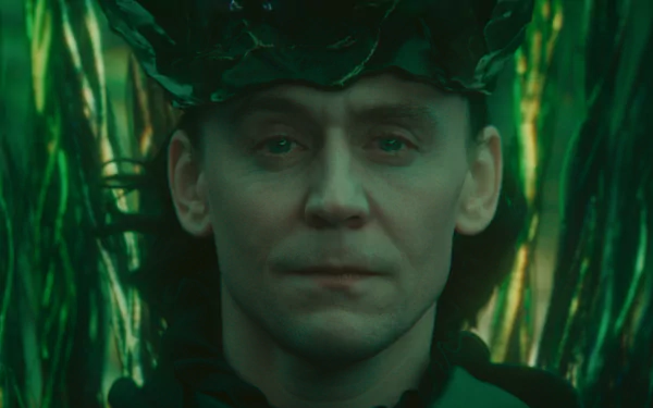 A striking HD wallpaper featuring Loki from Marvel Comics, portrayed by Tom Hiddleston, with an intense gaze against a backdrop of vibrant green foliage.