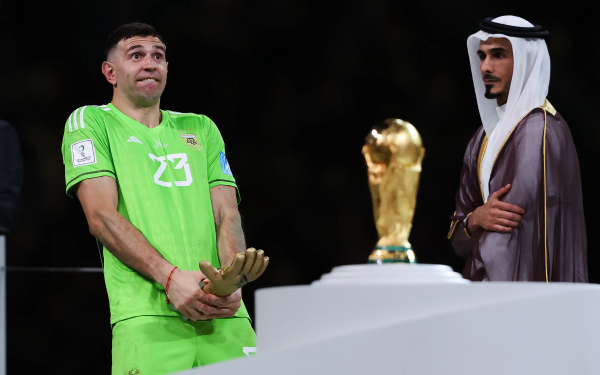 Soccer goalkeeper in green standing beside FIFA World Cup trophy, suitable for desktop wallpaper.