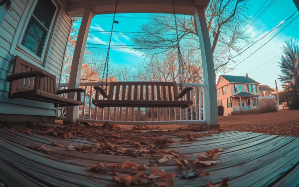 HD Wallpaper of a cozy porch swing bench with autumn leaves on a wooden deck, capturing serene suburban life.