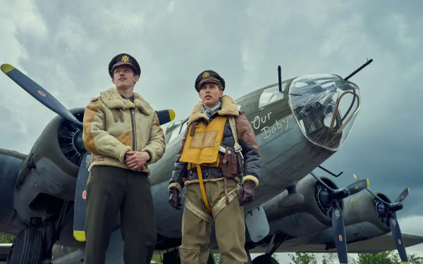 HD wallpaper featuring two actors from the TV show 'Masters of the Air' standing confidently in front of a vintage military aircraft, capturing the drama of World War II aviation.