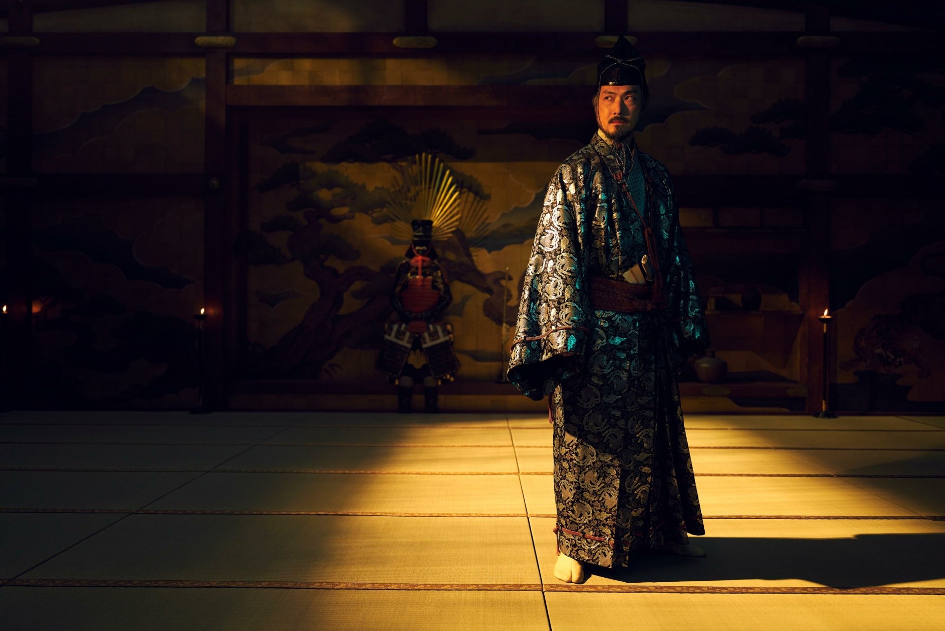 A striking scene from the TV show Shogun (2024), featuring a character in an ornate robe, illuminated by dramatic lighting in a traditional setting. An atmospheric HD wallpaper for fans.