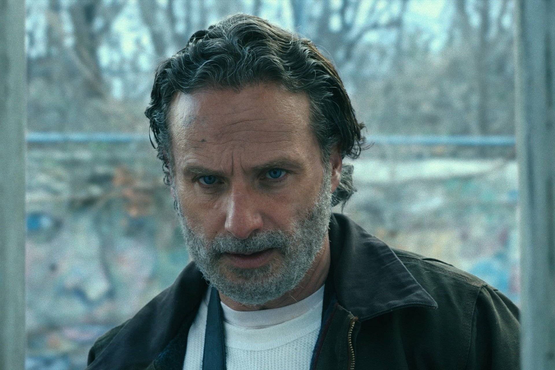 Rick Grimes, portrayed by Andrew Lincoln, is featured in this HD wallpaper from The Walking Dead: The Ones Who Live, capturing his intense expression against a dramatic backdrop.