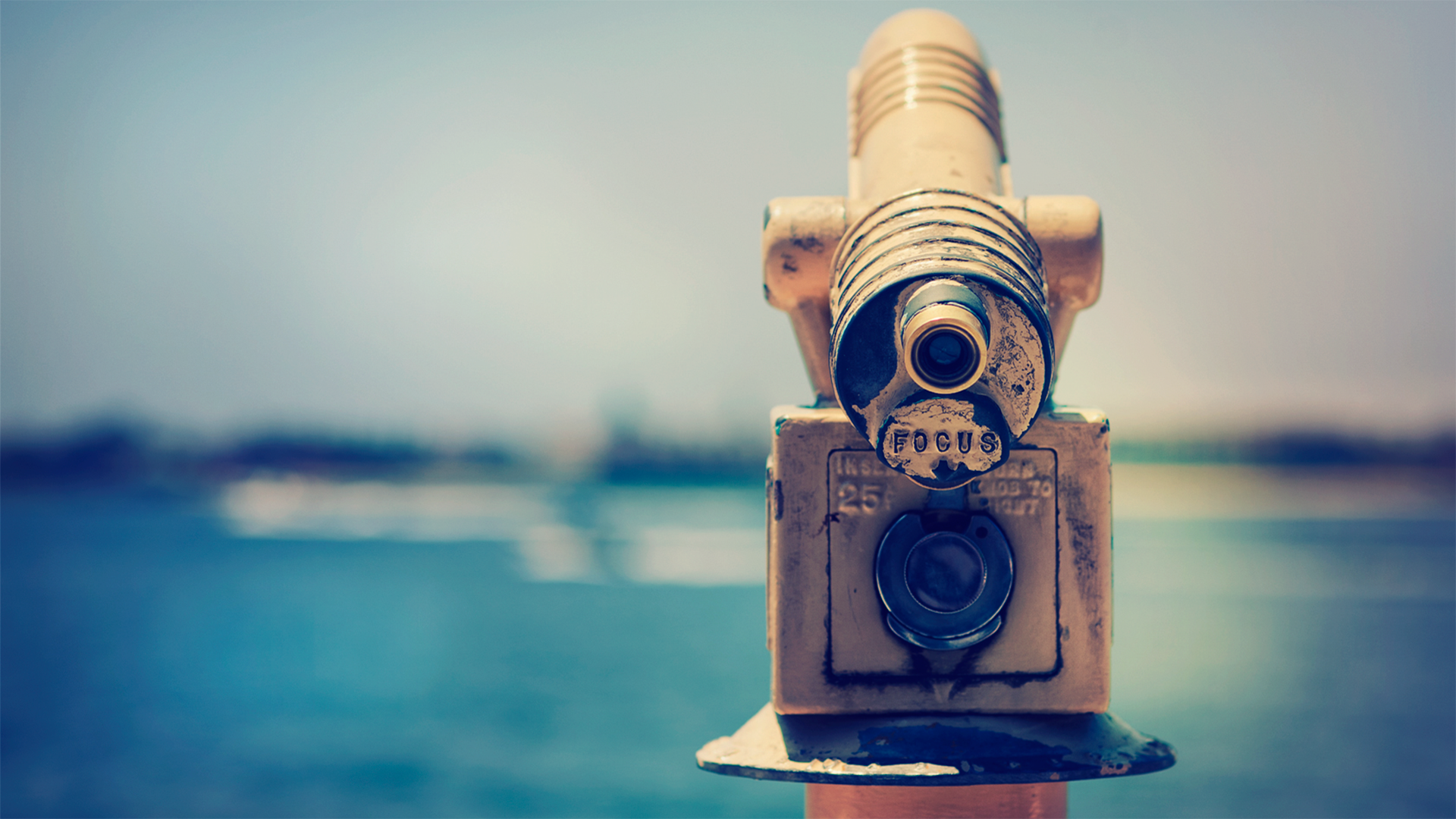 A close-up of a man-made telescope overlooking a serene body of water, set against a vibrant blue sky, creating a captivating HD desktop wallpaper.