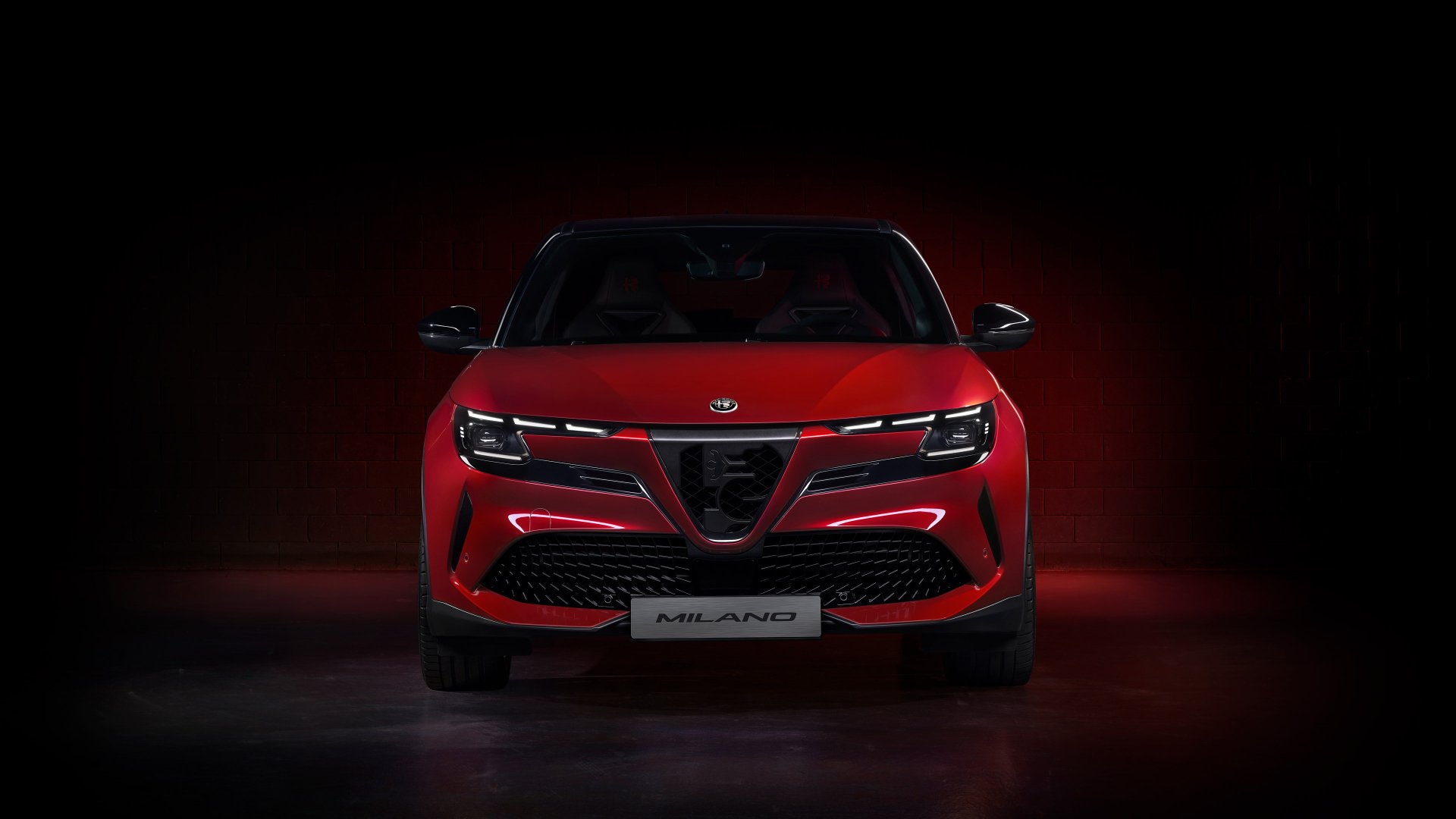 HD wallpaper of a red Alfa Romeo Milano Veloce car against a dark background with subtle lighting.