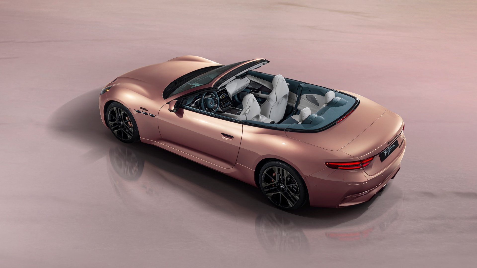 A sleek Maserati GranCabrio in a stunning rose gold finish with its top down, showcased as a high-definition desktop wallpaper.