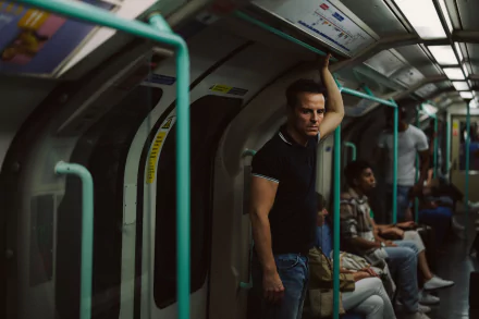 HD desktop wallpaper featuring a moody scene from the movie All of Us Strangers with a contemplative person standing in a subway car.