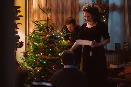 A festive scene from the movie All of Us Strangers, featuring a warm holiday setting with a decorated Christmas tree and characters engaged in joyful celebrations.