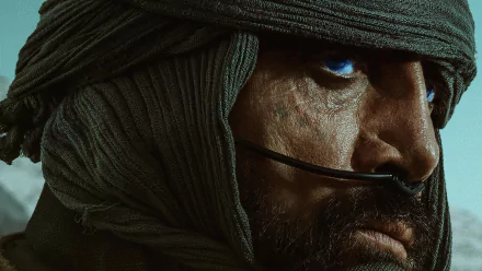 Close-up HD wallpaper featuring a character from the movie Dune (2021) with distinctive blue eyes, wrapped in a desert headscarf, intense and contemplative.